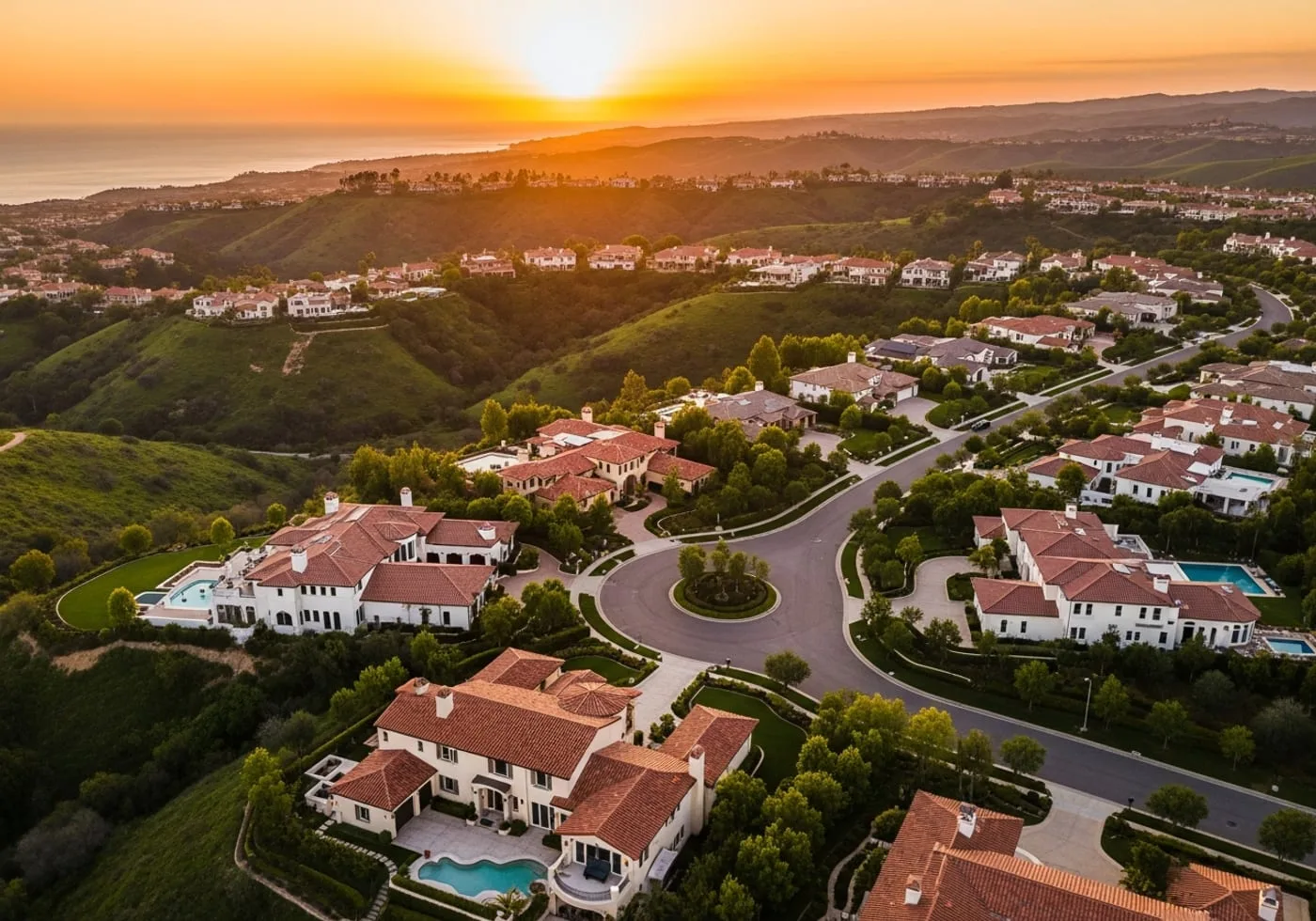Aerial sunset view of a luxury coastal Orange County hillside community with Mediterranean estates and the ocean beyond