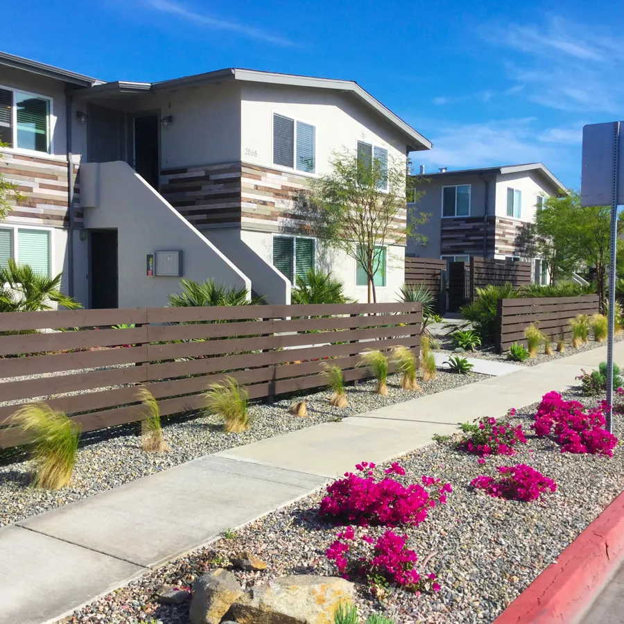 Walkway between modern homes lined with bougainvillea and a built-in wood bench
